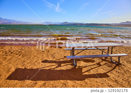 Picnic Table on Sandy Beach by Lake with Mountain Backdrop Eye Level View Picnic Table on Sandy Beach by Lake with Mountain Backdrop Eye Level View 129192178
