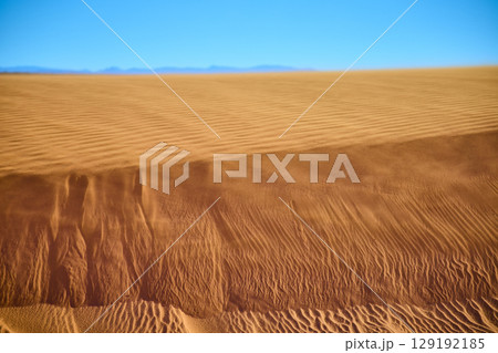 Golden Sand Dune Ripples with Distant Mountains and Blue Sky Eye Level 129192185