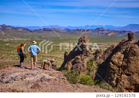 Hikers and Dog Exploring Rocky Desert Outcrop with Vast Valley Eye Level 129192378