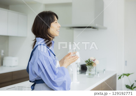 キッチンで水を飲む女性  129192771