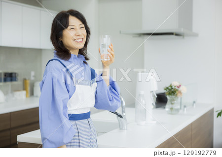 キッチンで水を飲む女性  129192779