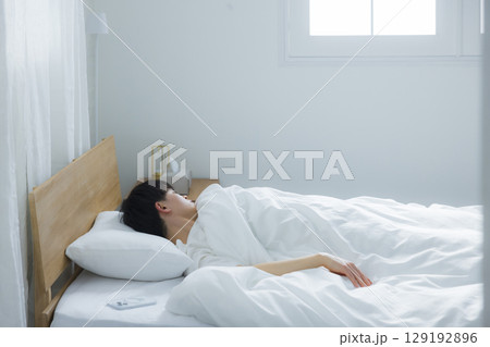 ベッドでスマホを使う若い男性 129192896