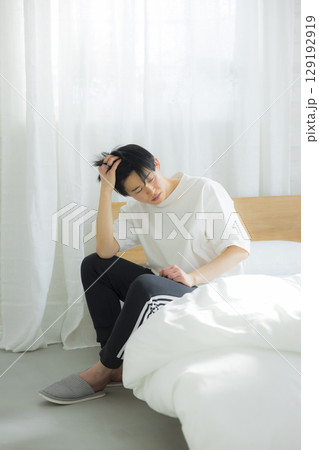 ベッドに座る若い男性 129192919