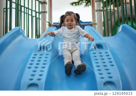 happy toddler baby girl sliding and playing at playground happy toddler baby girl sliding and playing at playground 129195015