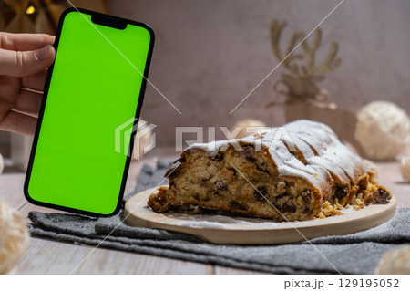 Homemade Christmas traditional cake pie with marzipan nuts and dried fruits pastry dessert stollen. Smartphone with green screen chroma key application website advertisement mock up template. Winter Homemade Christmas traditional cake pie with marzipan nuts and dried fruits pastry dessert stollen. Smartphone with green screen chroma key application website advertisement mock up template. Winter 129195052