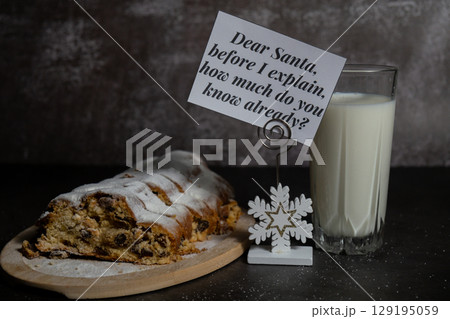 Paper note with message DEAR SANTA BEFORE I EXPLAIN HOW MUCH DO YOU KNOW ALREADY joke humor pun.Homemade Christmas traditional cake pie with marzipan nuts and dried fruits pastry dessert stollen with 129195059