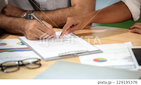 Man hand signing a contract on document for building house economic with architect and partner Man hand signing a contract on document for building house economic with architect and partner 129195376
