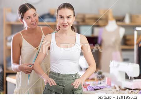 woman dressmaker taking measurements for a client woman dressmaker taking measurements for a client 129195612