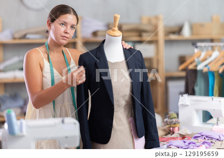 Young tailoress trying ready jacket on mannequin 129195659
