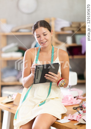 Young female dressmaker drawing on tablet in sewing workshop Young female dressmaker drawing on tablet in sewing workshop 129195670