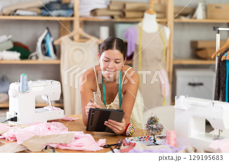 Female tailor create sketch of dress in tablet 129195683