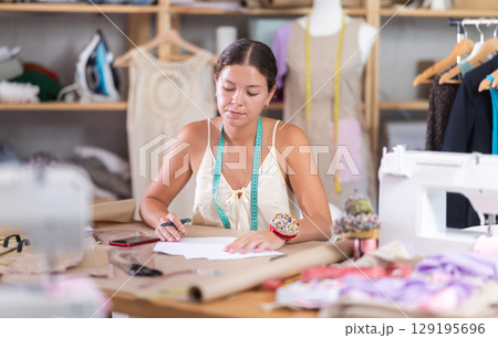 female dressmaker deals with documents in the atelier 129195696
