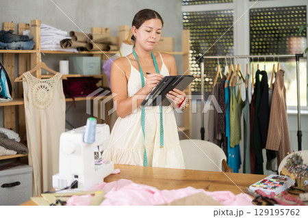Woman dressmaker drawing on tablet 129195762