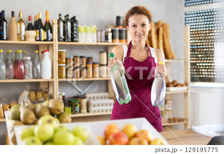Female salesperson offers to buy a bottle of mineral water in grocery supermarket Female salesperson offers to buy a bottle of mineral water in grocery supermarket 129195775