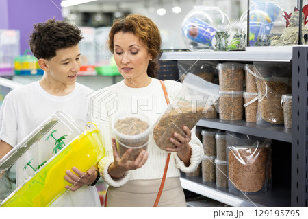 Family mom and son in animal goods store examines packaging of dry food for turtles Family mom and son in animal goods store examines packaging of dry food for turtles 129195795