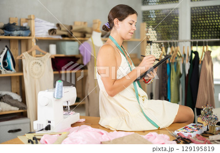 Female tailor create sketch of dress in tablet 129195819