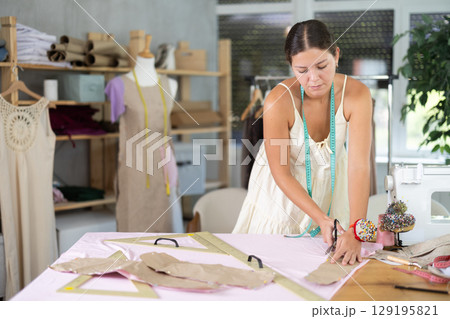 dressmaker marks and cuts the fabric 129195821