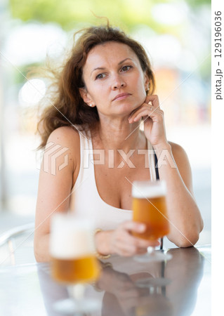 Adult woman drinking beer on cafe terrace Adult woman drinking beer on cafe terrace 129196036