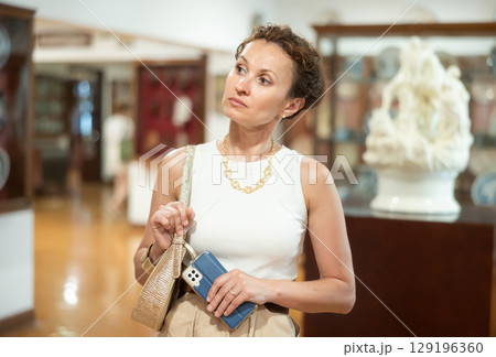Thoughtful woman examining historacal exhibits in museum 129196360