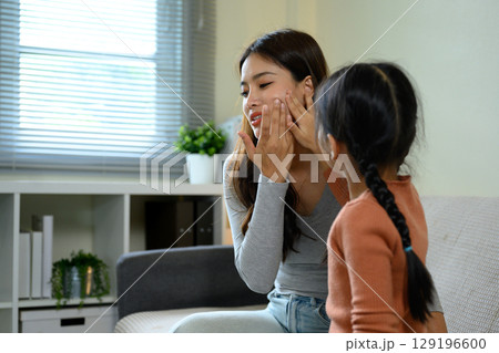 Happy mom and child bonding during beauty care routine in a living room Happy mom and child bonding during beauty care routine in a living room 129196600