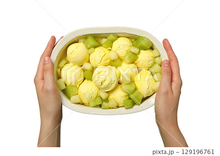 Hands hold a bowl of yellow ice cream and melon, isolated on white, PNG 129196761