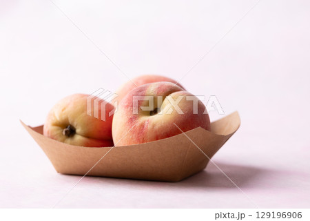 Fresh peaches in paper bowl on pink background, Summer fruit 129196906