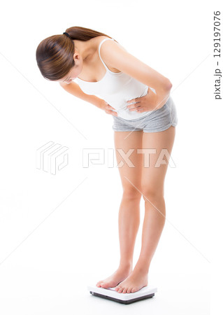 体重計に乗り体重をはかる若い女性. 129197076