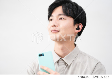 有線イヤホンで音楽を聴く若い男性 有線イヤホンで音楽を聴く若い男性 129197487