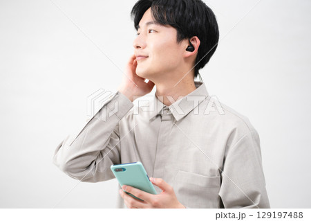 有線イヤホンで音楽を聴く若い男性 有線イヤホンで音楽を聴く若い男性 129197488