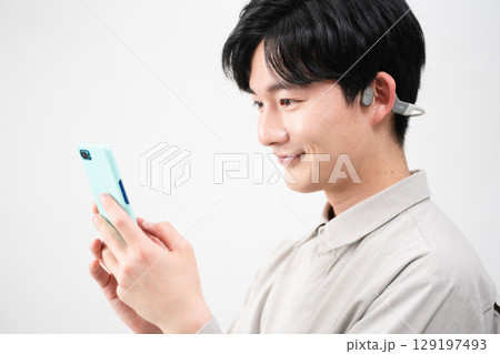 ワイヤレスイヤホンで音楽を聴く若い男性 ワイヤレスイヤホンで音楽を聴く若い男性 129197493