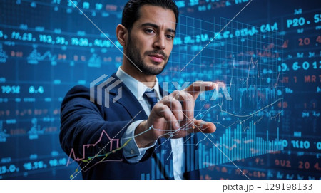 A young Middle-Eastern man in a suit interacts with digital financial data on a screen. He has dark hair and a focused expression. 129198133