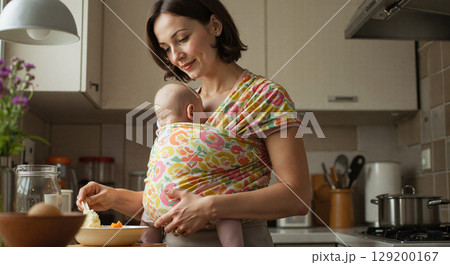 Mother caring for baby while cooking in a cozy kitchen 129200167