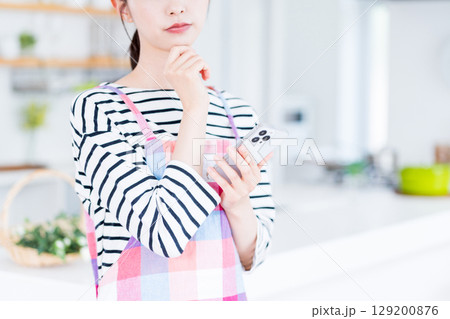 献立を迷ってスマホで検索している主婦。 献立を迷ってスマホで検索している主婦。 129200876