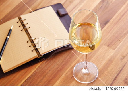 白ワインを飲みながら、リング式のシステム手帳に日記をつけているイメージ写真 129200932