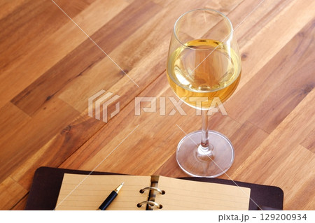白ワインを飲みながら、リング式のシステム手帳に日記をつけているイメージ写真 129200934