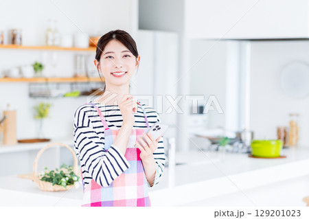 献立を迷ってスマホで検索している主婦。 献立を迷ってスマホで検索している主婦。 129201023