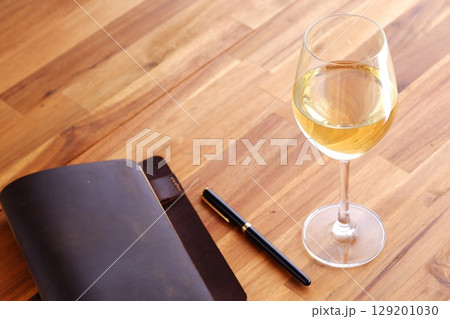 白ワインを飲みながら、茶色の革のシステム手帳に日記をつけているイメージ 白ワインを飲みながら、茶色の革のシステム手帳に日記をつけているイメージ 129201030