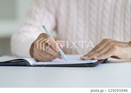 ペンを持ったシニア男性の手元 129201046