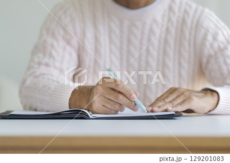 ペンを持ったシニア男性の手元 129201083