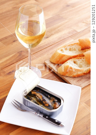 缶詰のオイルサーディンとバゲット、白ワインのグラス 缶詰のオイルサーディンとバゲット、白ワインのグラス 129201251