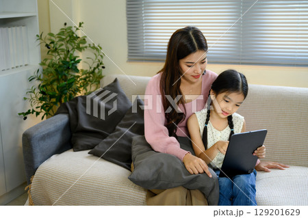 Mother and daughter using digital tablet together, enjoying online learning or entertainment Mother and daughter using digital tablet together, enjoying online learning or entertainment 129201629
