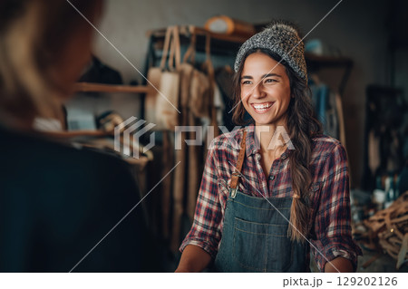 Smiling woman plaid shirt denim apron beanie shop cheerful casual indoor Smiling woman plaid shirt denim apron beanie shop cheerful casual indoor 129202126