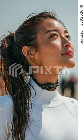 Confident korean woman enjoying sunny day at beach, gazing at clear sky and feeling the breeze during outdoor activity Confident korean woman enjoying sunny day at beach, gazing at clear sky and feeling the breeze during outdoor activity 129202648