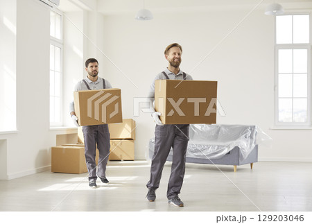 Two busy man movers carrying cardboard boxes with belongings, working in relocation service 129203046