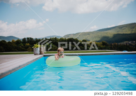 Little girl playing in shallow water in pool, using swim ring. Little girl playing in shallow water in pool, using swim ring. 129203498