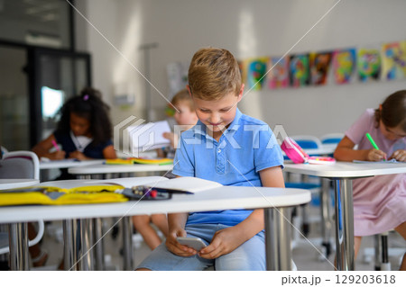 Schoolboy distracted by mobile phone during lesson. Schoolboy distracted by mobile phone during lesson. 129203618