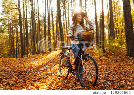 Happy active young woman on bike in autumn park at sunset. Concept of people, recreation, active lifestyle. 129205666