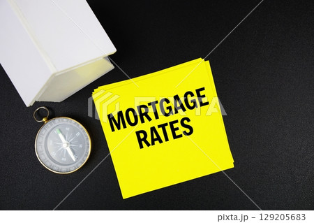 Mortgage Rates text message with white house model and magnifying glass top view on black background 129205683