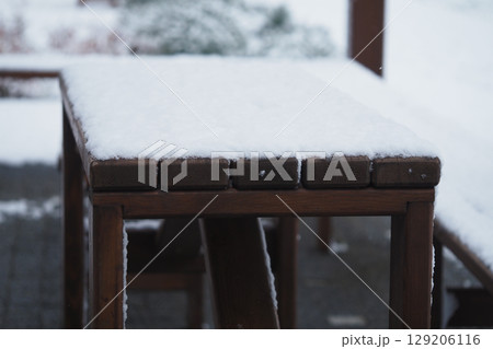 Snow covers a wooden outdoor table in winter setting 129206116