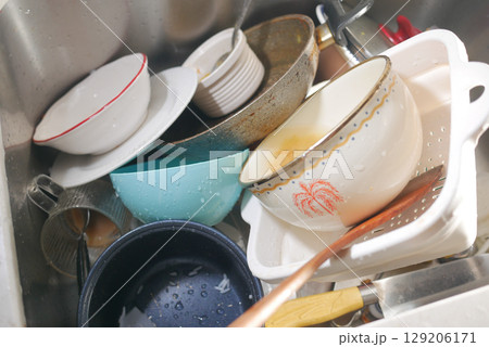 Dishes piled high in a kitchen sink after dinner cleanup Dishes piled high in a kitchen sink after dinner cleanup 129206171